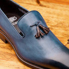 Close view of Blue leather loafer with a tassel on a wooden surface