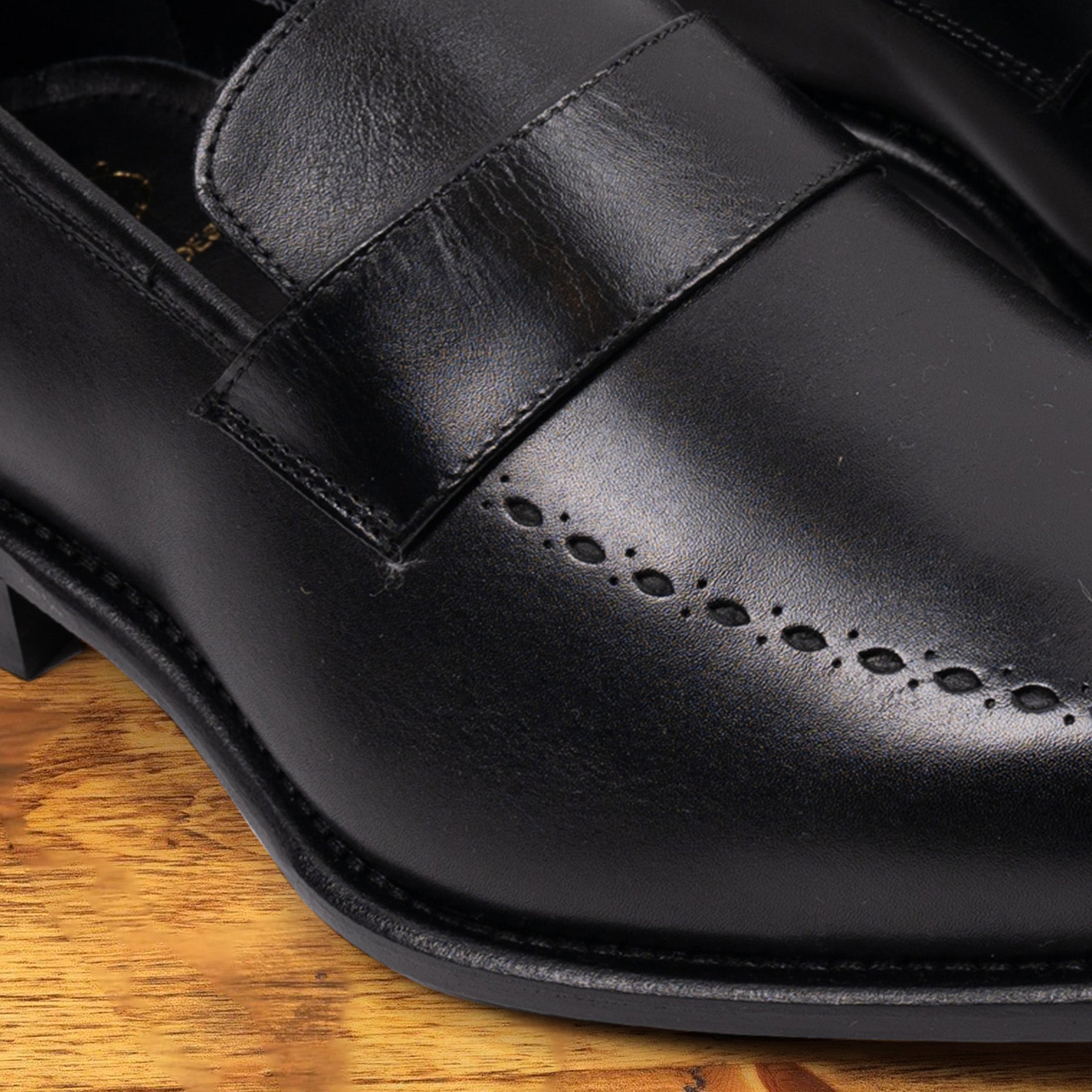 Black leather loafer on a wooden surface 