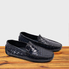 A Pair of Blue crocodile-patterned loafer on a wooden surface with a light gray background