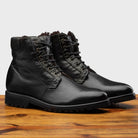 Pair of Black leather boots on a wooden surface