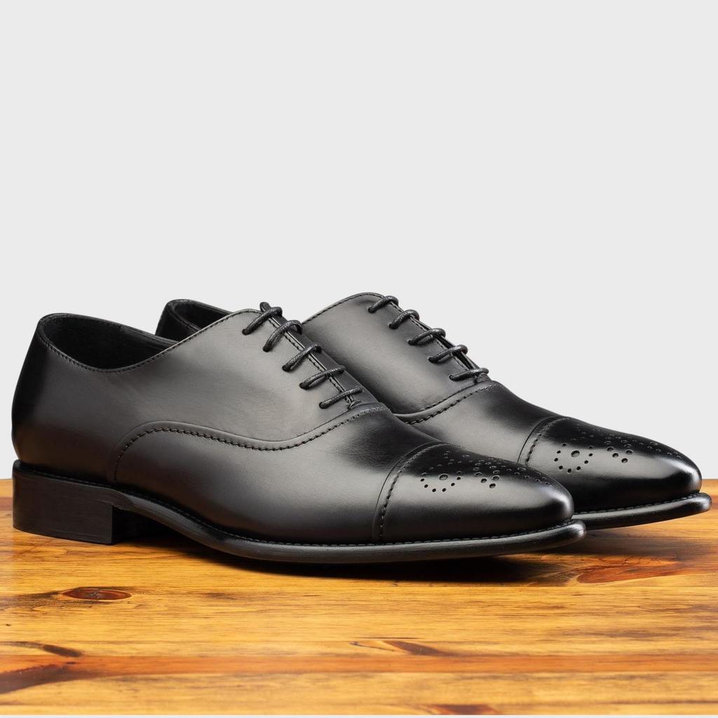 Pair of Black leather dress shoe on a wooden surface with a white background