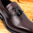 Close view of Porpora leather loafer with a tassel on a wooden surface