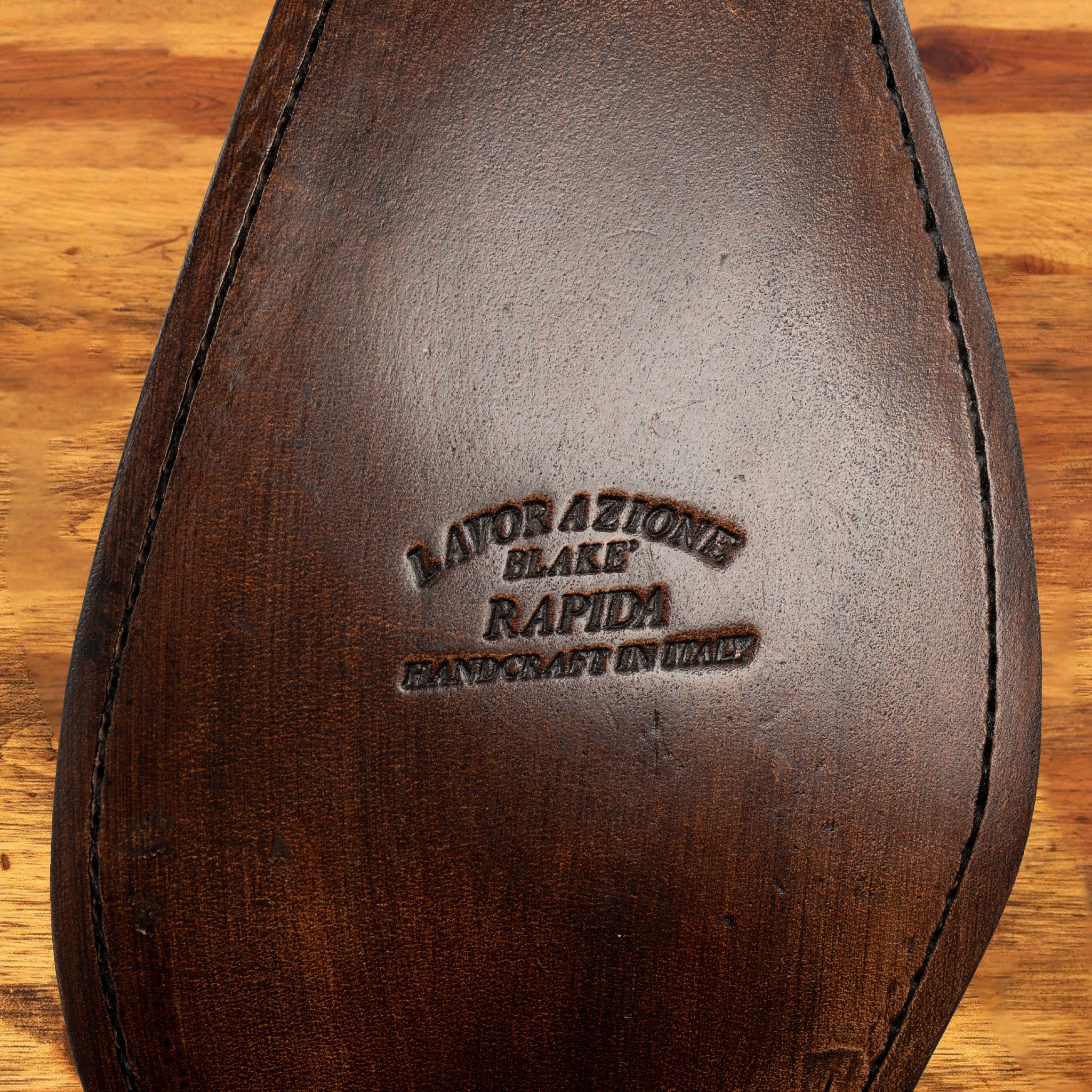 Outsole of Caramel leather dress shoe on a wooden surface 